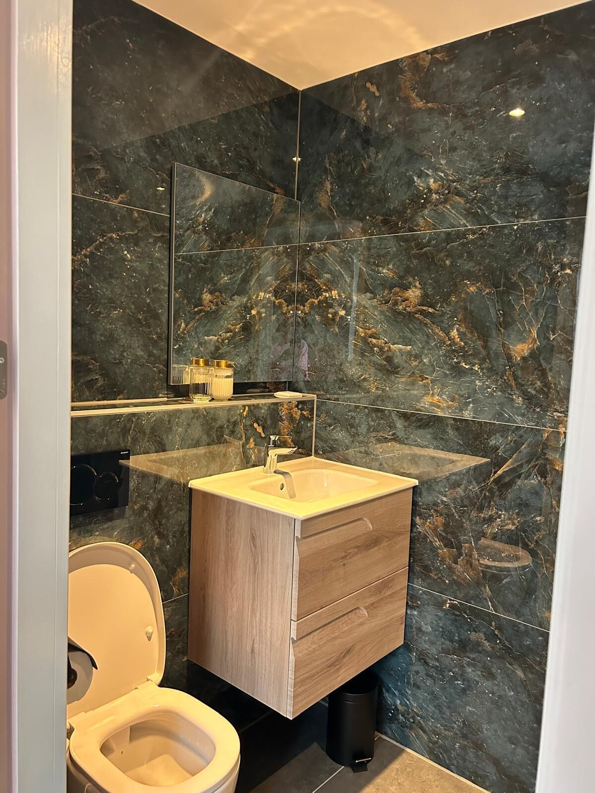Une salle de bain moderne avec un meuble-lavabo en marbre, des toilettes et un grand miroir.