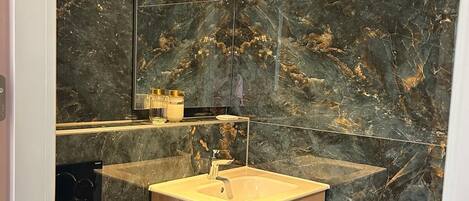 Une salle de bain moderne avec un meuble-lavabo en marbre, des toilettes et un grand miroir.
