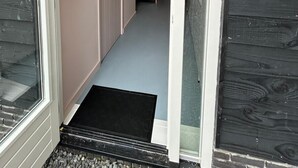 En smal hall som leder till ett sovrum med en säng och ett fönster.