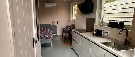A compact kitchen with a built-in stove, a sink, and a window with a view of trees.