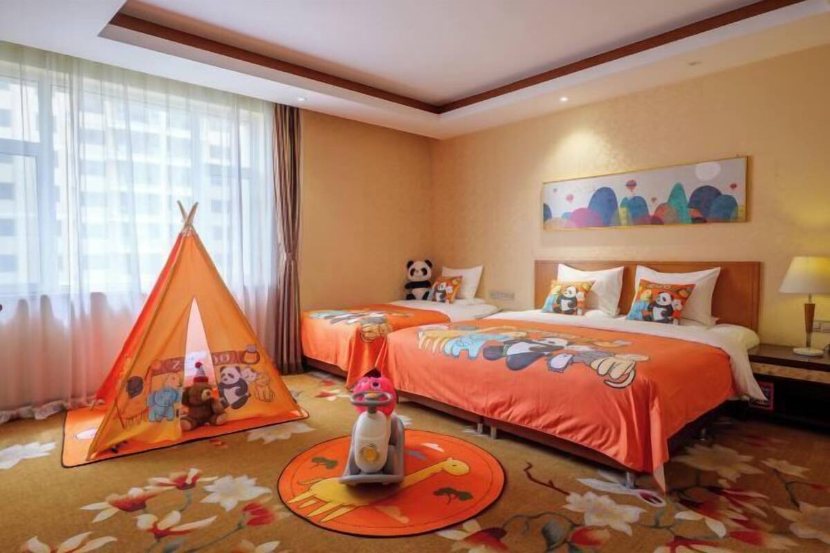 A hotel room with a bed, a play tent, and a toy car.
