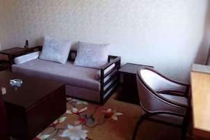 Una habitación con un sofá, una silla, una mesita y un tapete decorativo.