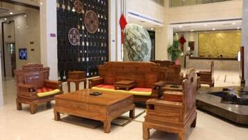 A lobby with traditional wooden furniture, a reception desk, and a decorative wall with circular patterns.