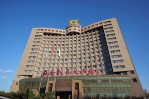 Een hotel met meerdere verdiepingen, een opvallende ingang en een grote glazen gevel.