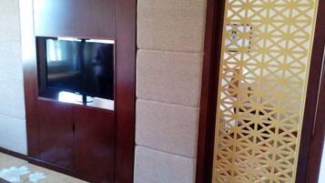 A room with a wooden entertainment unit, a television, and a decorative partition.