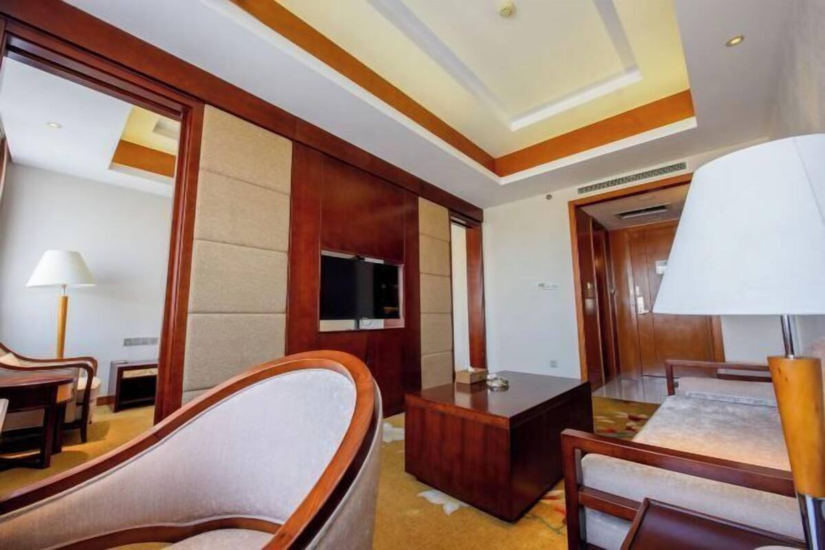 A hotel room with a large bed, a TV, a desk, and a chair.