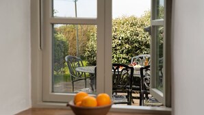 A view through a window with a bowl of oranges on a table. - Cosy Rural Garden Cottage Sea Views Near St Ives (Cornwall)