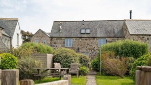 A stone building with a gravel path leading to a wooden table and chairs. - Cosy Rural Garden Cottage Sea Views Near St Ives (Cornwall)