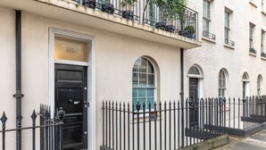 A building with a black door, a balcony with plants, and a warning sign. - The Tachbrook at No. 195: 6-Bed Historic Townhouse | Victoria (London)