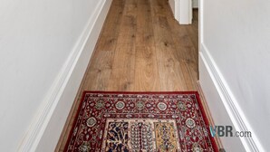 A hallway with wooden flooring, a red patterned rug, and framed artwork on the walls. - The Tachbrook at No. 195: 6-Bed Historic Townhouse | Victoria (London)