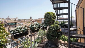 A balcony with potted plants and a view of a cityscape with historical buildings. - Exclusive Roman Attic: Between Vatican, Trastevere & Piazza Navona (Roma)