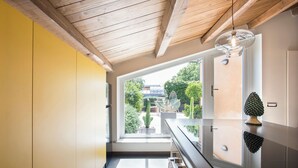 A modern kitchen with a wooden ceiling, a large window, and a view of greenery outside. - Exclusive Roman Attic: Between Vatican, Trastevere & Piazza Navona (Roma)