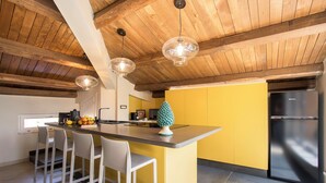 A modern kitchen with wooden beams, a yellow accent wall, and a stainless steel refrigerator. - Exclusive Roman Attic: Between Vatican, Trastevere & Piazza Navona (Roma)