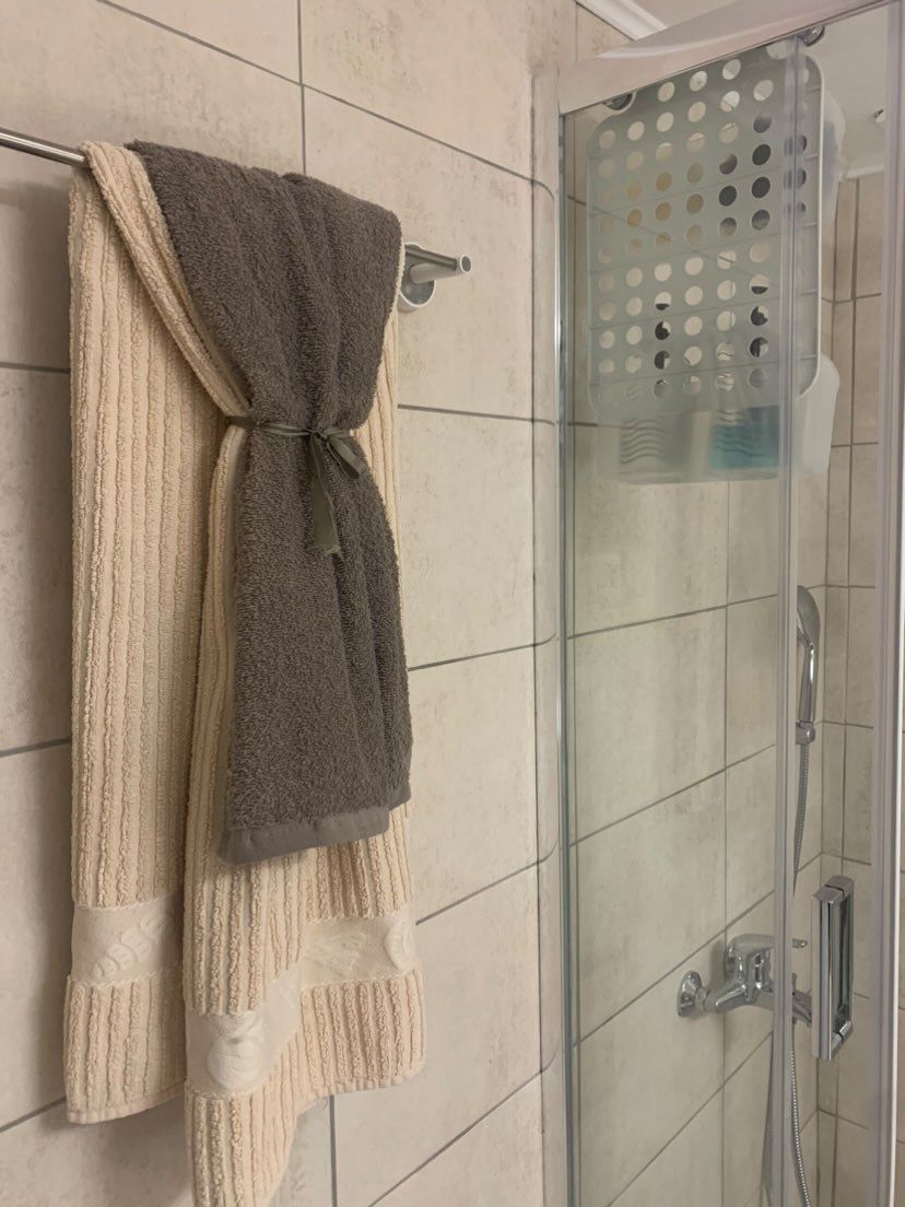 A bathroom with a glass shower enclosure, a towel rack with a folded towel, and a showerhead.