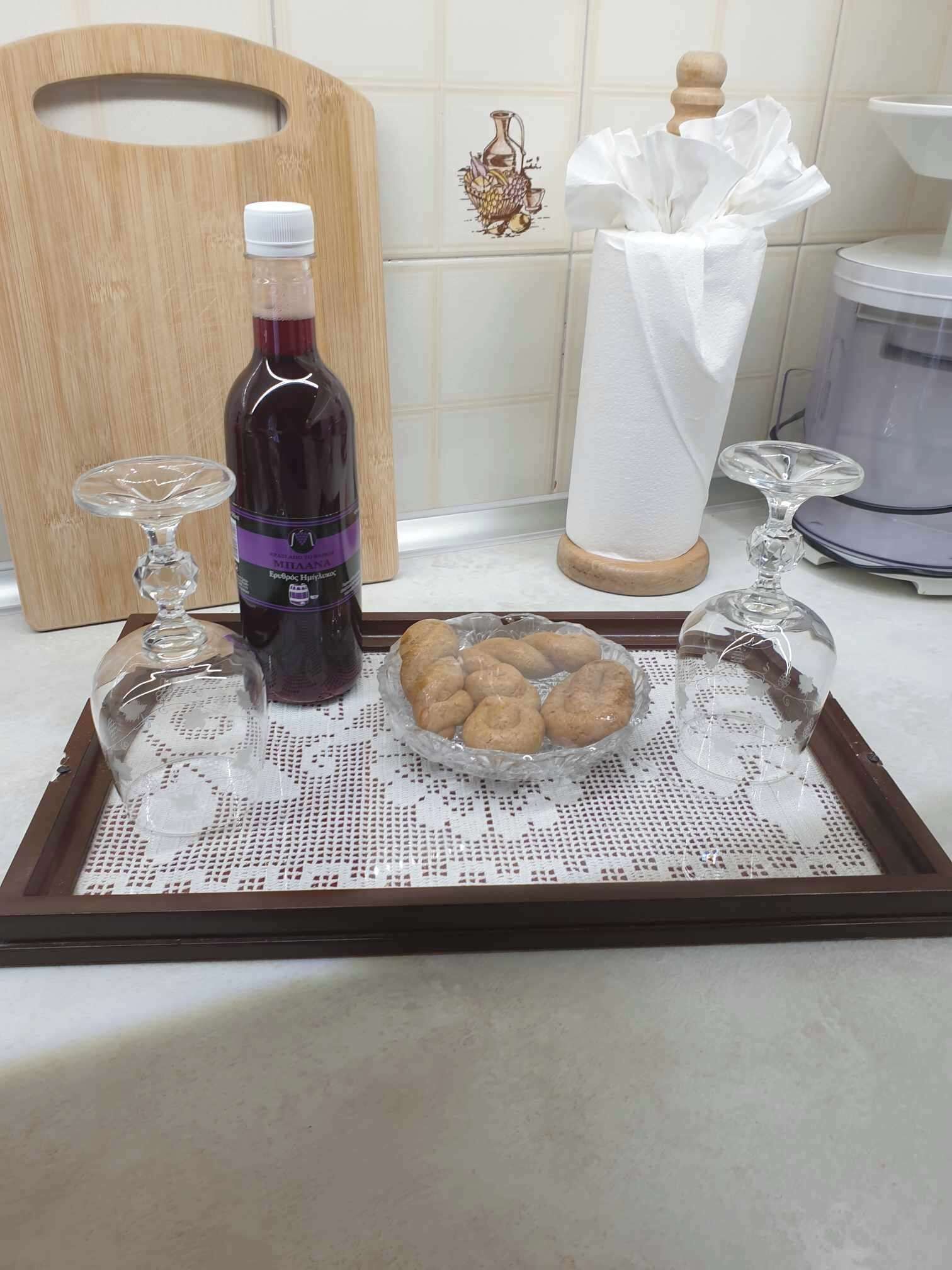Una bandeja con una botella de vino tinto, una copa y galletas sobre un posavasos de encaje.
