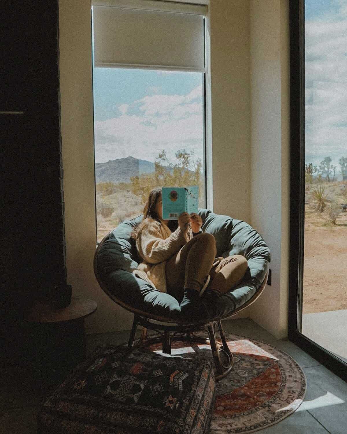 Una habitación con un ventanal grande, un sillón redondo y una alfombra estampada.