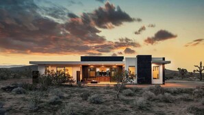 Una casa moderna con techo plano, ventanas amplias y un patio.
