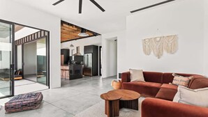 Una sala moderna con un sofá modular, una mesa de centro y un tapiz de macramé en la pared.