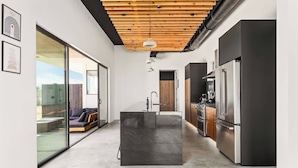 Una cocina moderna con una isla central, electrodomésticos de acero inoxidable y techo de madera.