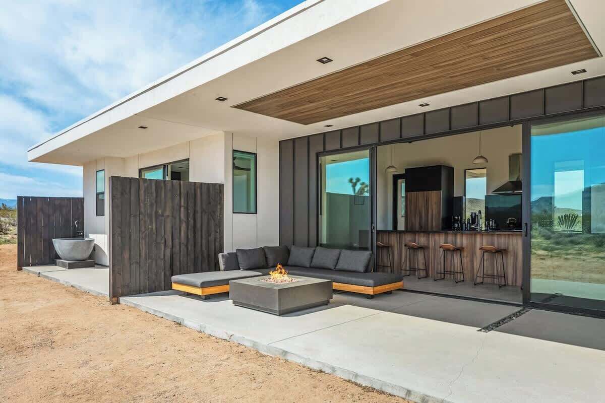 Ein modernes Haus mit Terrasse, Sitzgelegenheiten im Freien und einer Bar.