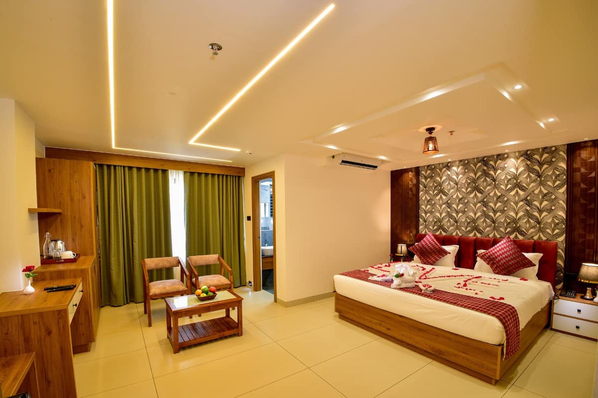 A modern hotel room with a large bed, wooden furniture, a desk, and a green curtain.