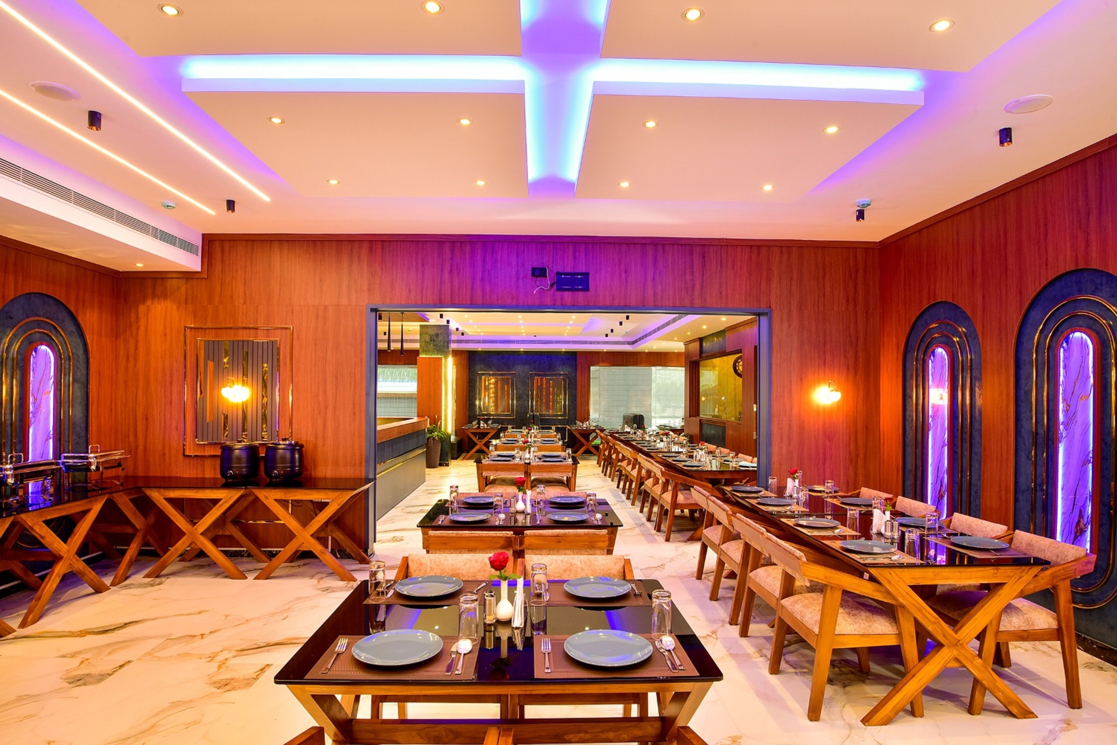 A spacious dining area with long tables, wooden paneling, and modern lighting.