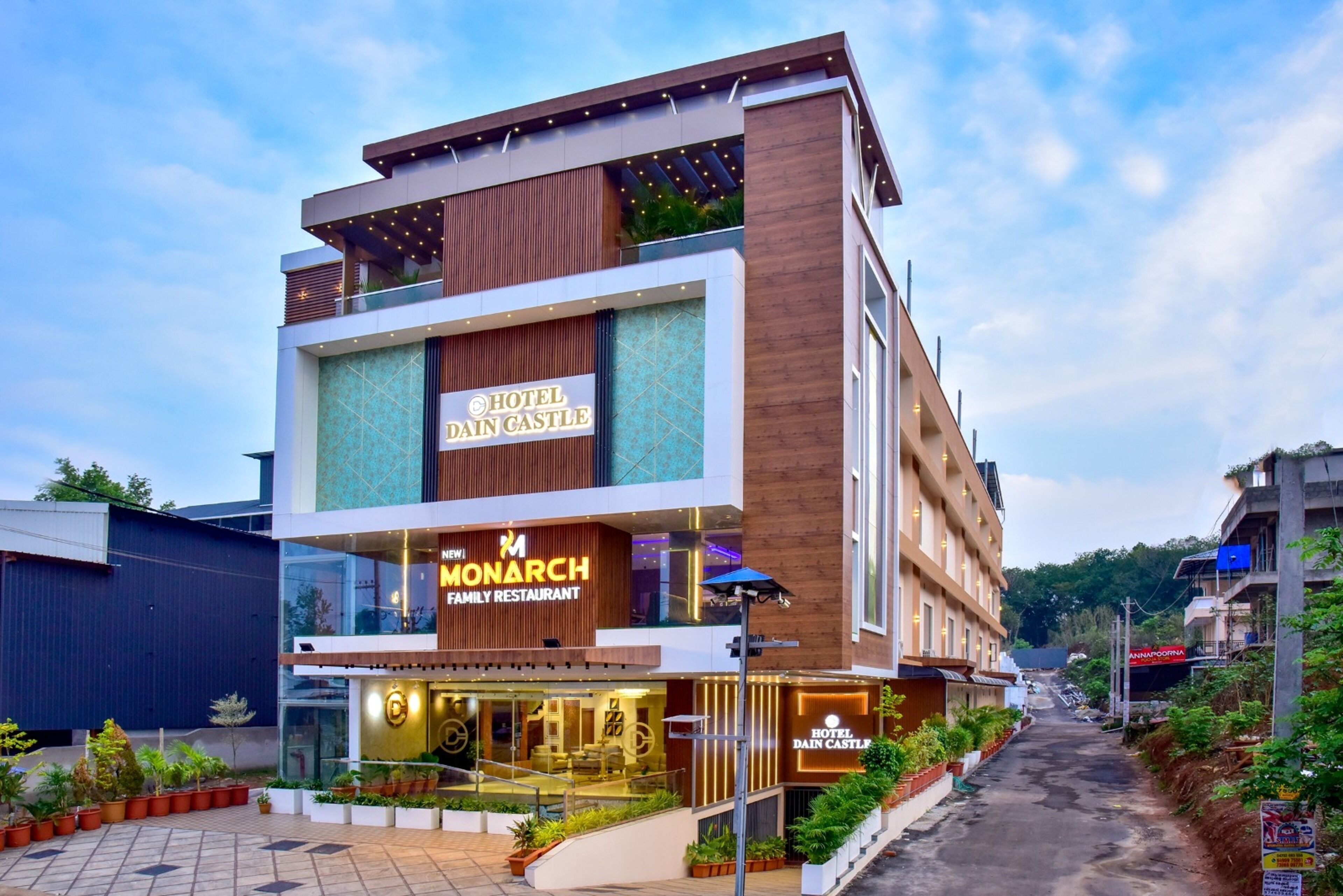 Un hotel moderno con una estructura de dos pisos, un restaurante familiar y un espacio exterior bien cuidado con plantas en macetas.