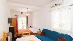 A bedroom with a bed, a blue sofa, a small table with fruit, and a TV. - Apartments Felix Mljet (Mljet)