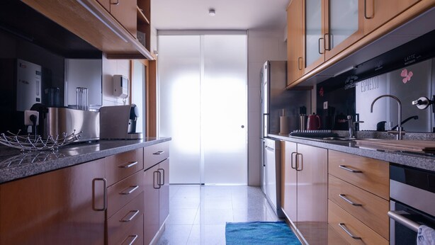 Una cocina moderna con armarios de madera, electrodomésticos de acero inoxidable y una alfombra azul en el suelo.
