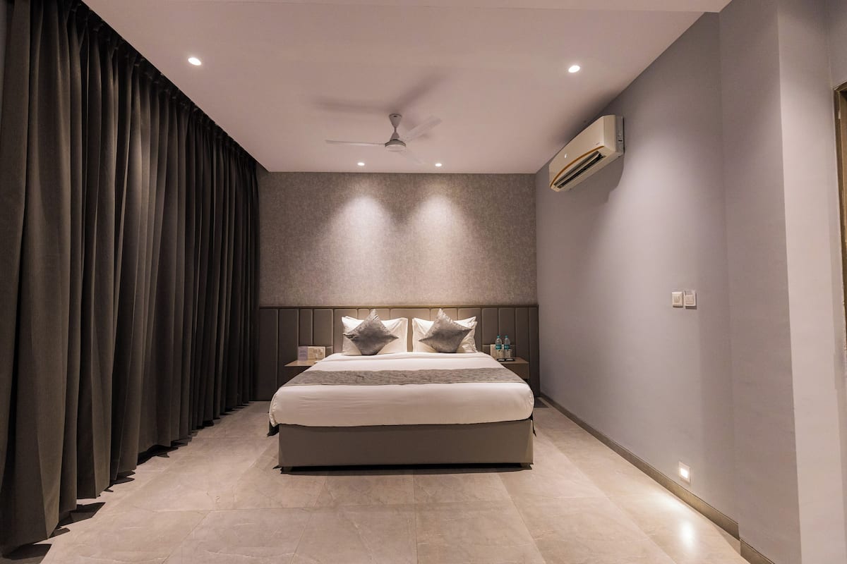 Un dormitorio moderno con una cama grande, ventilador de techo, iluminación empotrada y un equipo de aire acondicionado.