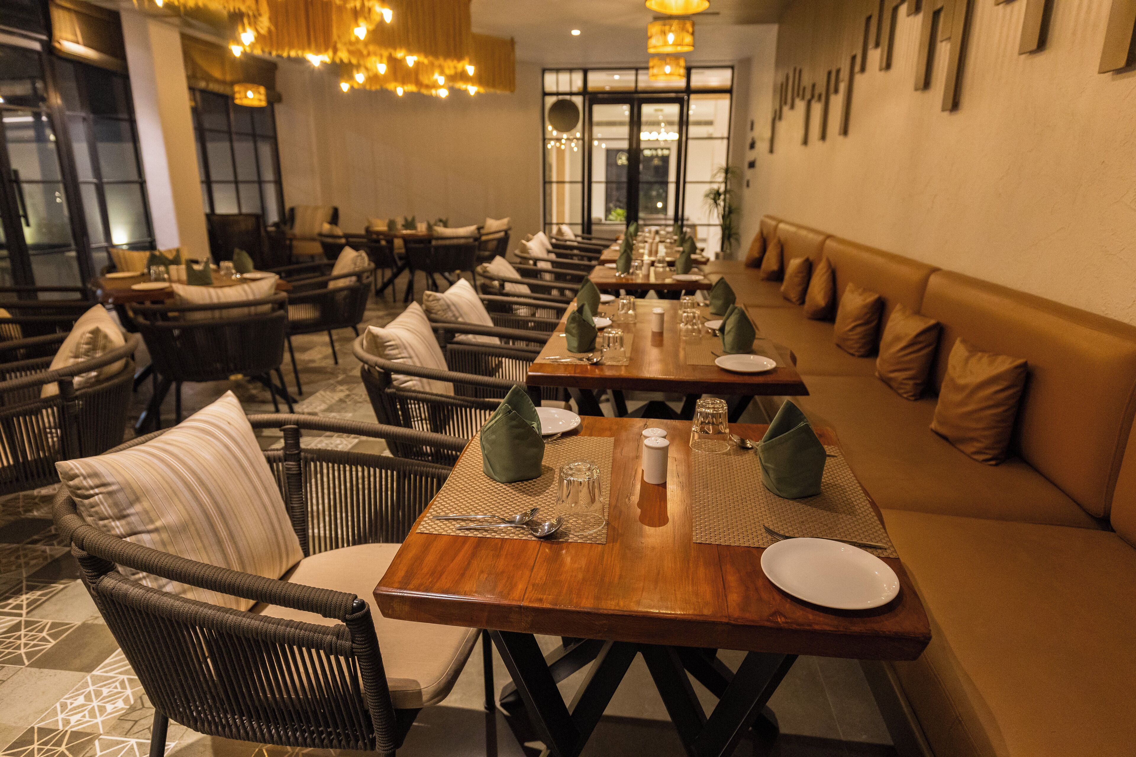 A restaurant with long communal tables, cushioned seating, and a warm interior.