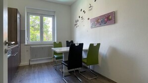 Un coin repas avec une table et des chaises, une fenêtre donnant sur un beau paysage et un mur décoré sur le thème du café.