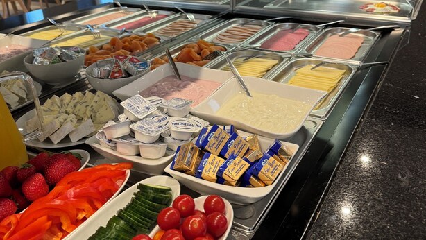 Un bufé con diversas opciones de comida, incluyendo carnes, quesos y frutas.