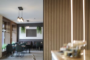 A modern restaurant interior with wooden paneling, hanging pendant lights, and green plants. - Skyline Hotel  (Hannover)