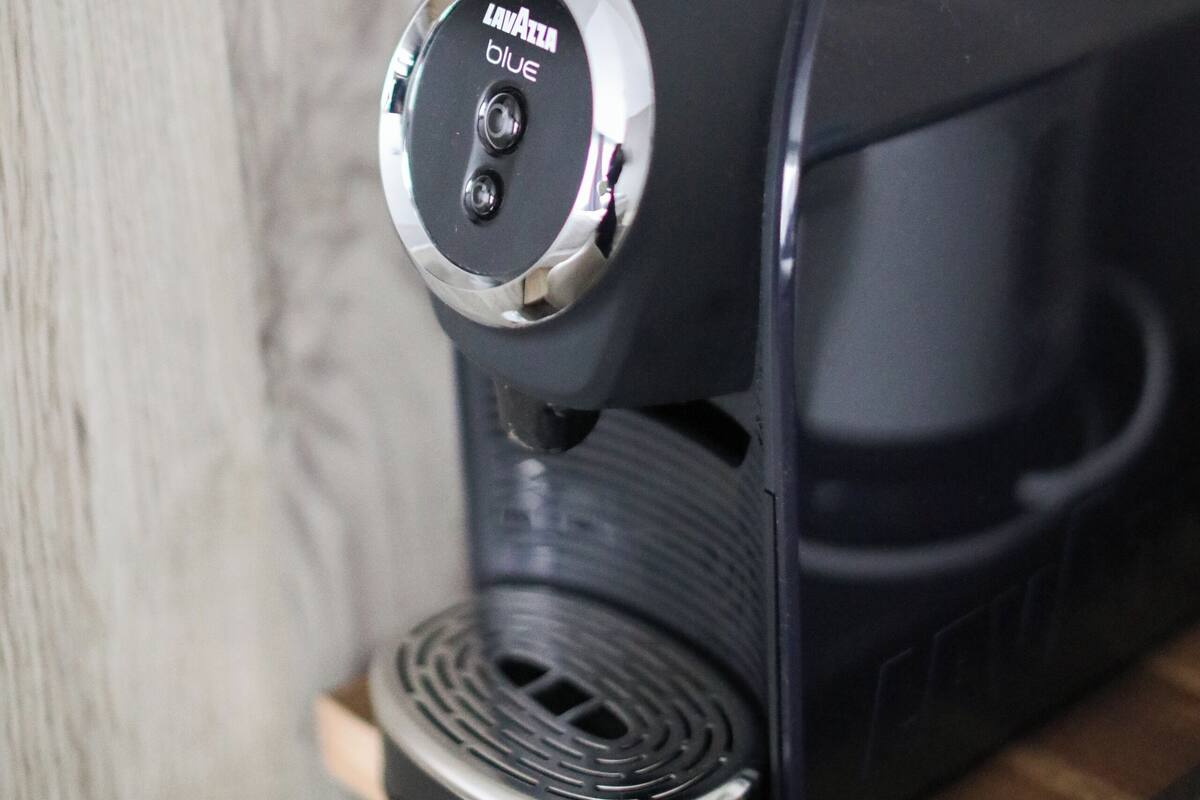 Una cafetera portátil negra con parte superior plateada y una etiqueta que dice 'Lavazza Blue'.