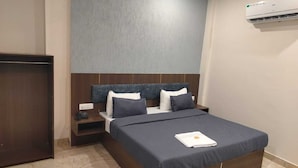 Une chambre d’hôtel équipée d’un lit, d’une table de chevet, d’une armoire et d’un appareil de climatisation.