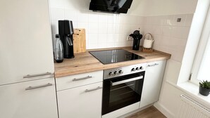 Una cocina moderna con armarios blancos, una estufa negra y una encimera de madera.