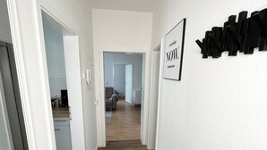 Un pasillo con suelo de madera, paredes blancas y un cartel enmarcado en la pared.