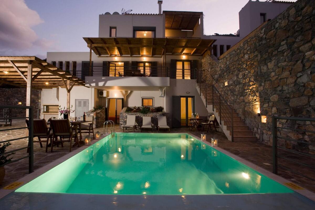 A modern building with a swimming pool, stone walls, and outdoor seating.