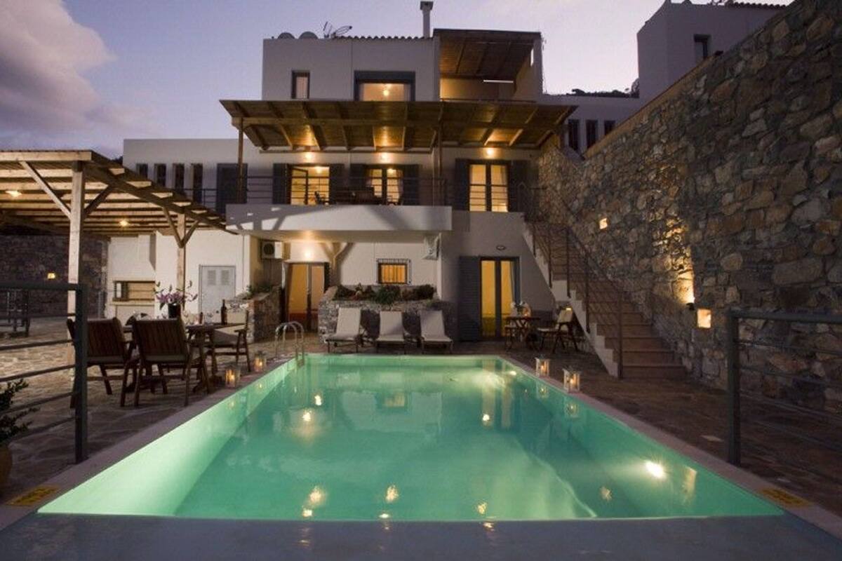 A modern building with a swimming pool, outdoor seating, and stone walls.