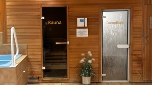 Der Eingang zu einer Sauna und einem Dampfbad mit Holzverkleidung, einer Glastür und einem Blumentopf.