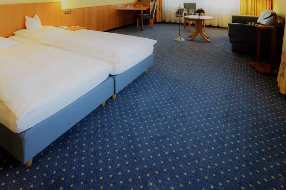 A hotel room with two beds, a small table, a chair, and a desk.