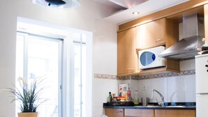 A modern kitchen with wooden cabinets, a microwave, and a refrigerator. There is a glass table with a chair and a potted plant. - Super Studio IN THE Heart OF Trendy Gracia By Myrentalhost (Barcelona)