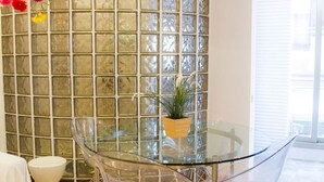 A modern room with a glass table, clear chairs, a potted plant, and a decorative wall with a grid pattern. - Super Studio IN THE Heart OF Trendy Gracia By Myrentalhost (Barcelona)