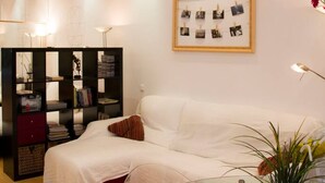 A modern living room with a white sofa, a glass coffee table, and a bookshelf. - Super Studio IN THE Heart OF Trendy Gracia By Myrentalhost (Barcelona)