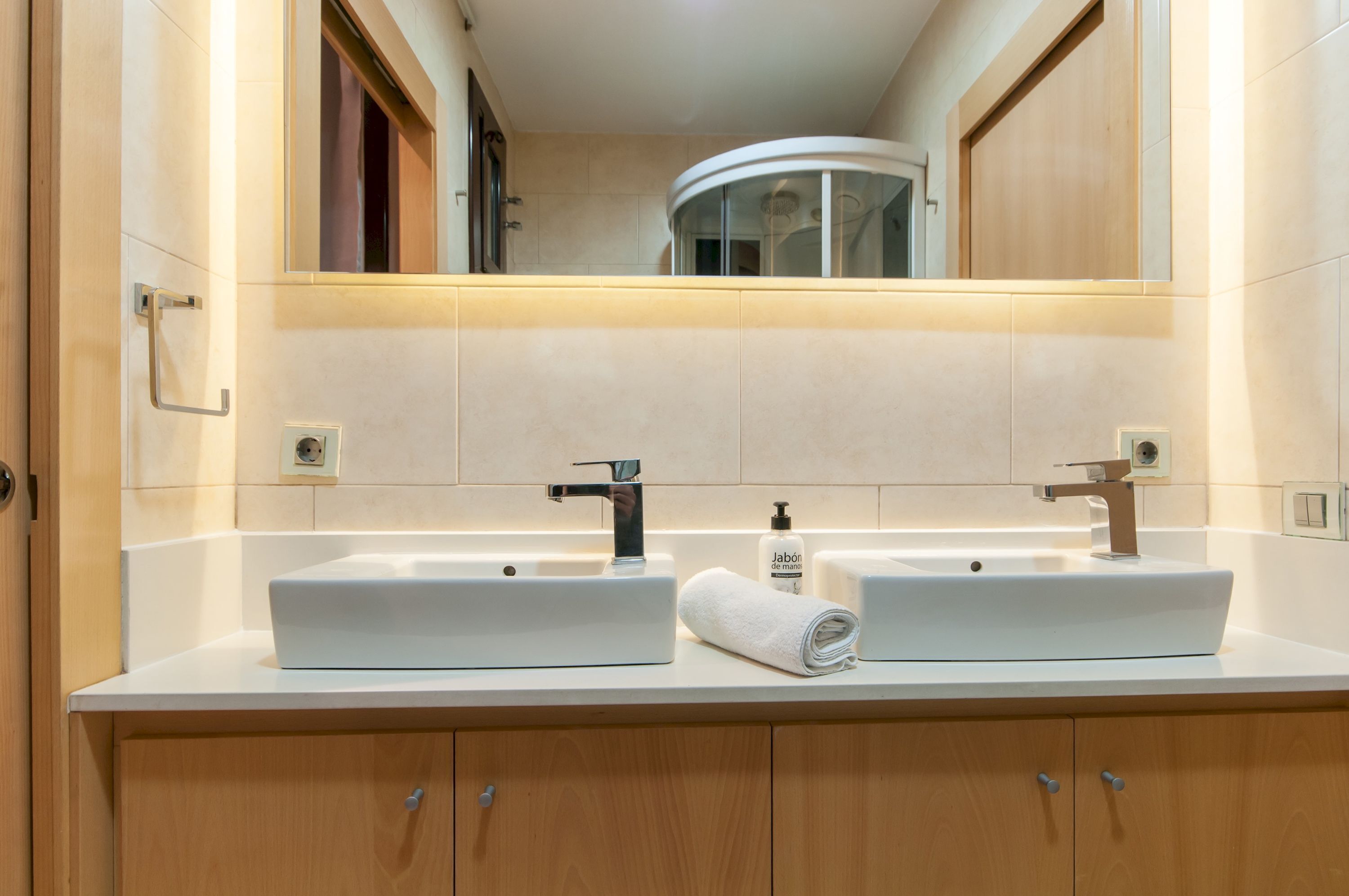 A bathroom with two sinks, a mirror, and a towel.