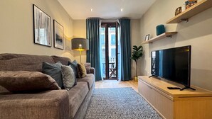 A living room with a sofa, a TV, a lamp, and a view to the outside.