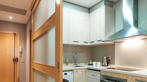 A compact kitchen with wooden cabinets, a washing machine, a dishwasher, and a stove.