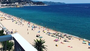 A beach with a clear view of the sea and a hill in the background.
