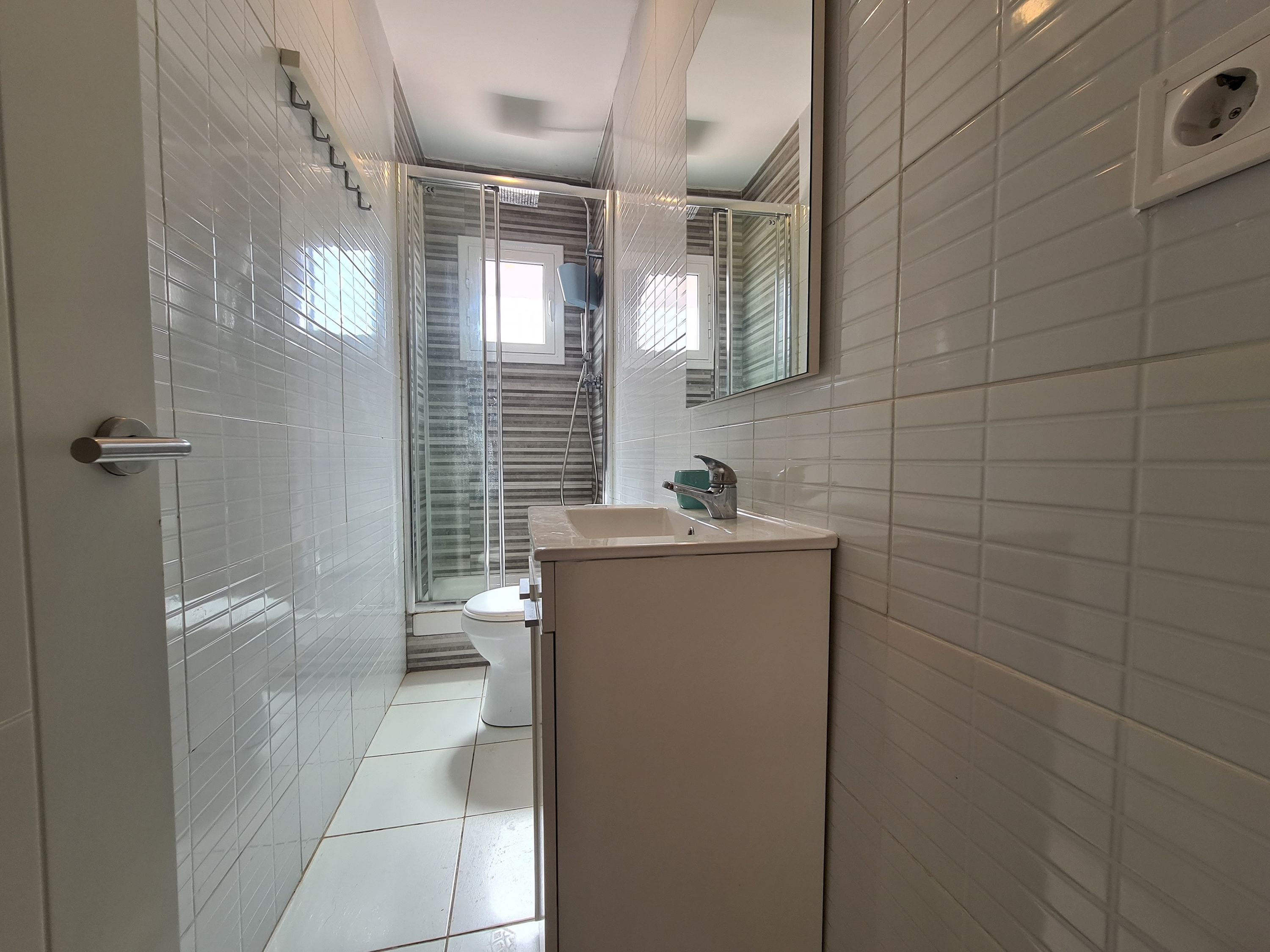 Un bagno moderno con cabina doccia in vetro, lavandino bianco e toilette.